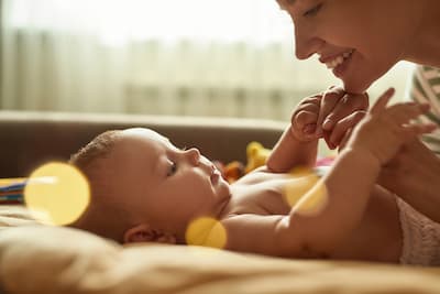 Mother smiling at her baby while they hold each others hands